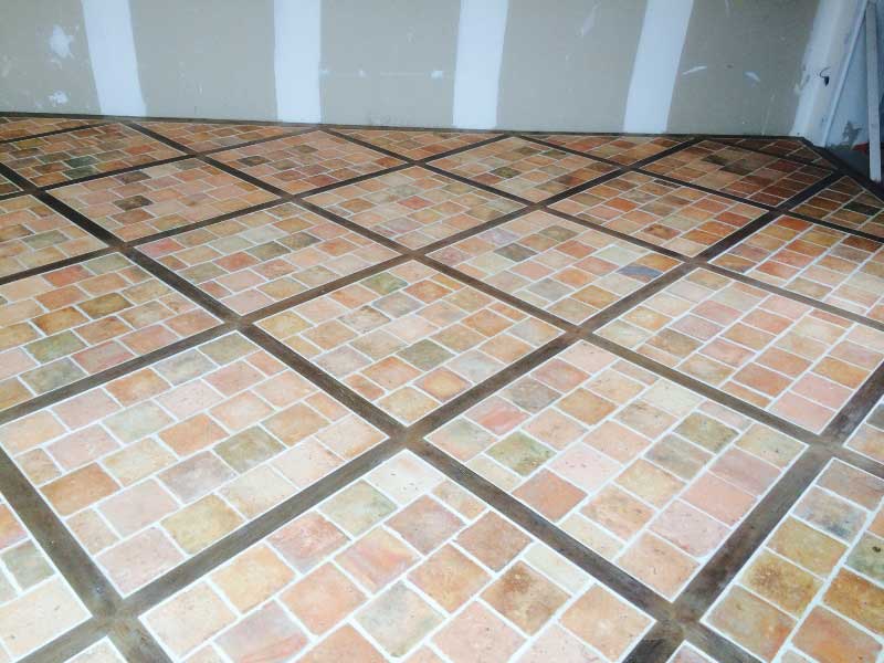 Carrelage ancien de terre cuite posé entre des lattes de parquet en chêne ancien